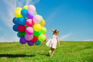 A small girl holding balloons
